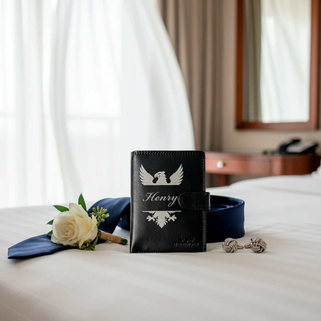 Personalized black leather wallet with name Henry, navy blue belt, white rose, and cufflinks on white bed